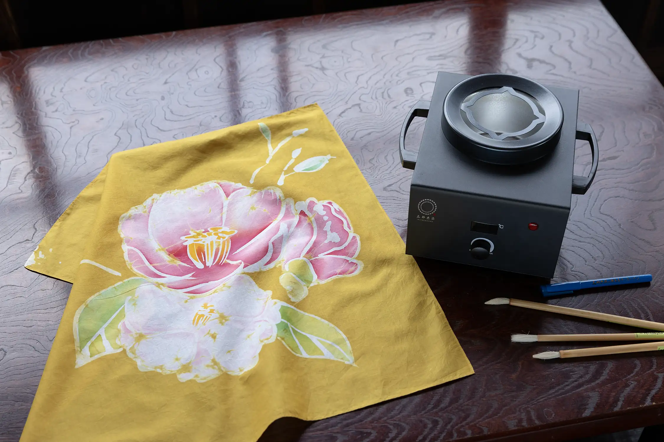 みやこ染 ろう溶器とろうけつ染目を行った椿の絵柄のハンカチが机の上に並んでいる